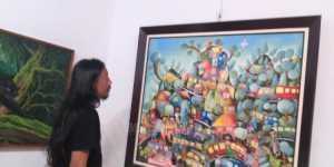Riyanto Sinyo memperhatikan salah satu lukisannya yang penuh warna
