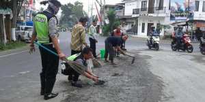 Sejumlah petugas kepolisian Polres Batu membersihkan tumpahan semen cor di pertigaan Pendem.2