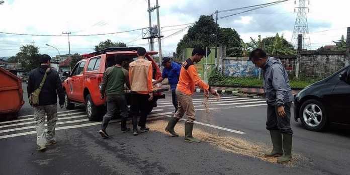 Petugas BPBD saat menabur serbuk gergaji di Jalan Dewi Sartika