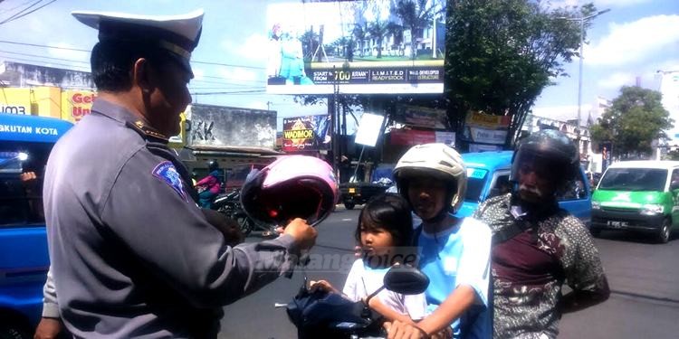 Kanit Dikyasa Polres Malang Kota, Ipda Endiex, saat memasangkan helm pada anak. (deny)