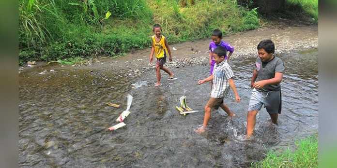 Anak-anak di area wisata Coban Talun bermain balap perahu dari pelepah pisang di aliran Sungai Brantas.(Miski)