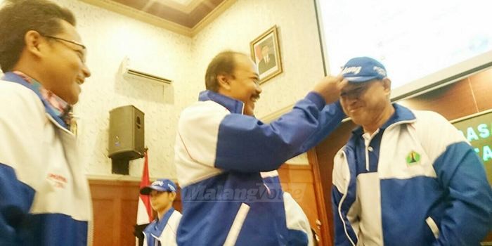 Kadispora Kota Malang, Nuzul Nurcahyo, menyematkan seragam kontingen secara simbolik kepada official tim. (Muhammad Choirul)