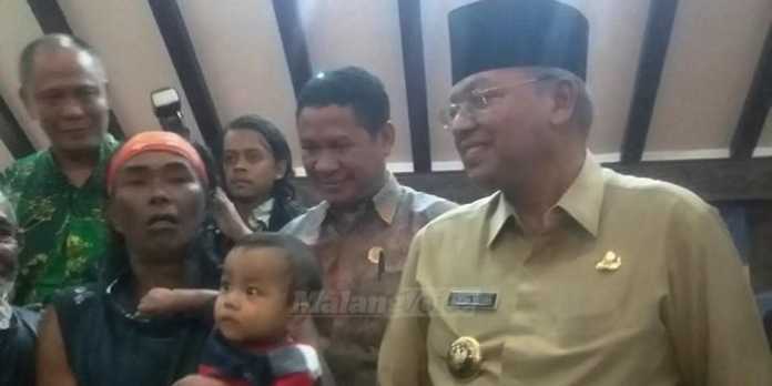 Pejalan mundur, Tarpin Iswahyudi, sambil menggendong anaknya, disambut Bupati Malang, Rendra Kresna. (Muhammad Choirul)