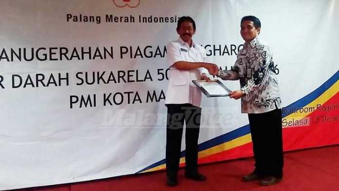 Ketua PMI Kota Malang, Bambang Priyo Utomo, menyerahkan penghargaan kepada pendonor 50 kali. (Muhammad Choirul)