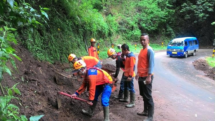 Petugas BPBD ketika membersihkan material longsoran di jalur Payung-Pujon.(miski)