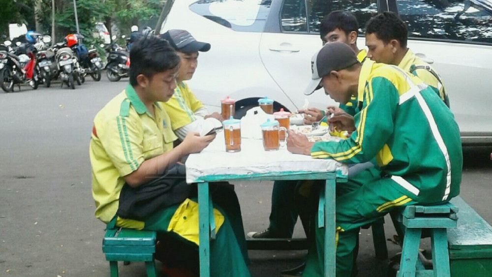 Petugas Pasukan Kuning menikmati hidangan makan gratis di Warung Isor Nongko. (Muhammad Choirul)