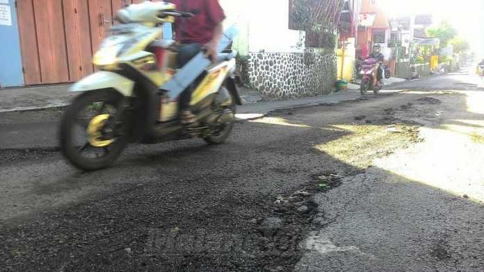 Pengendara sepeda motor saat melintas sebelum jalan di Dusun Dawuhan, Desa Tegalgondo diaspal ulang dengan cara tambal sulam.(Miski)
