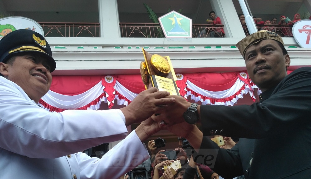 Wali Kota Malang, HM Anton, menyerahkan piala Adipura Kencana kepada Ketua DPRD Kota Malang, Arief Wicaksono. (Muhammad Choirul)