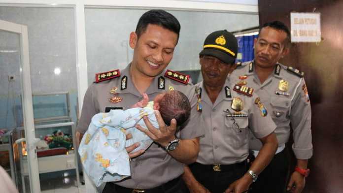 Kapolres Batu AKBP Budi Hermanto menggendong bayi di RS Bhayangkara Hasta Brata Kota Batu, Senin sore (4/9). (istimewa)