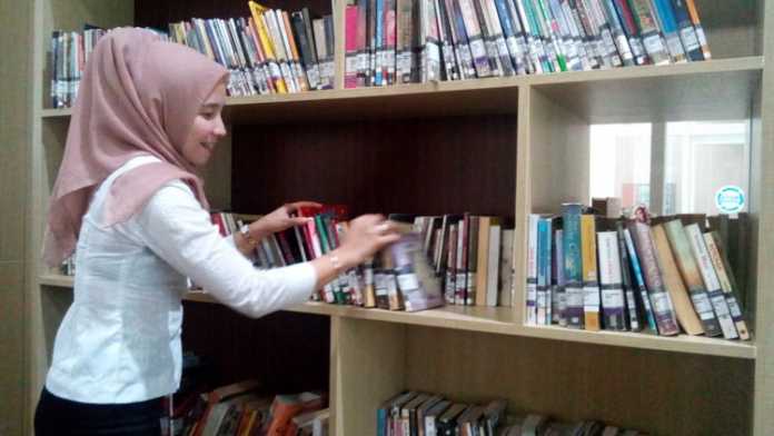 Staf dari Dinas Perpustakaan dan Kearsipan Kota Batu menata buku di Perpustakaan Balai Kota Among Tani, Rabu (18/10). (Aziz Ramadani)