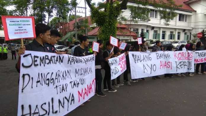 Segenap aktivis MCW bersama mahasiswa menggelar aksi di depan Balai Kota Malang. (Muhammad Choirul)
