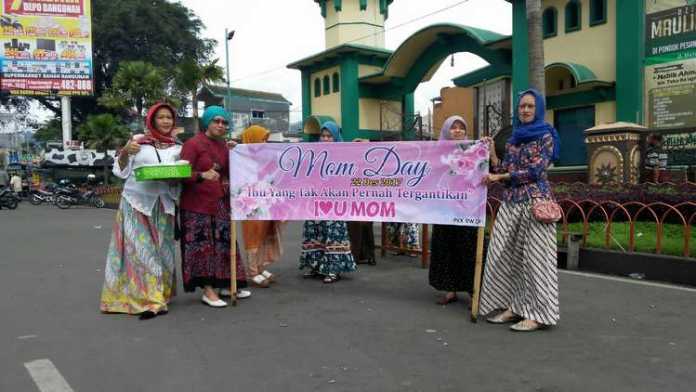 Para ibu dari RW09 Kelurahan Sisir Kecamatan Batu bagikan minuman gratis di Jalan Gajah Mada, Jumat (22/12). (Aziz Ramadani/MVoice)