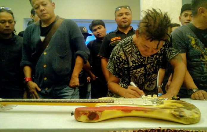 Tony Q Rastafara membubuhkan tanda tangan gitar miliknya di Galeri Musik Dunia, Sabtu (16/12). (Aziz Ramadani/MVoice)