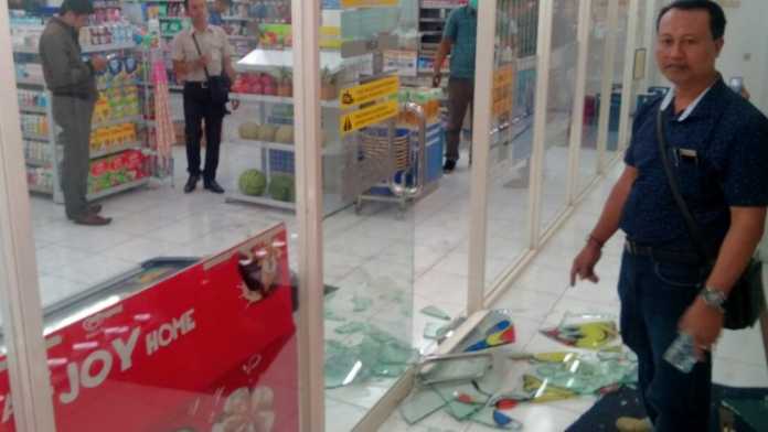 Petugas membersihkan sisa pecahan kaca pintu Indomaret Jalan Beji dibobol maling, Jumat pagi (26/1). (Aziz / MVoice)
