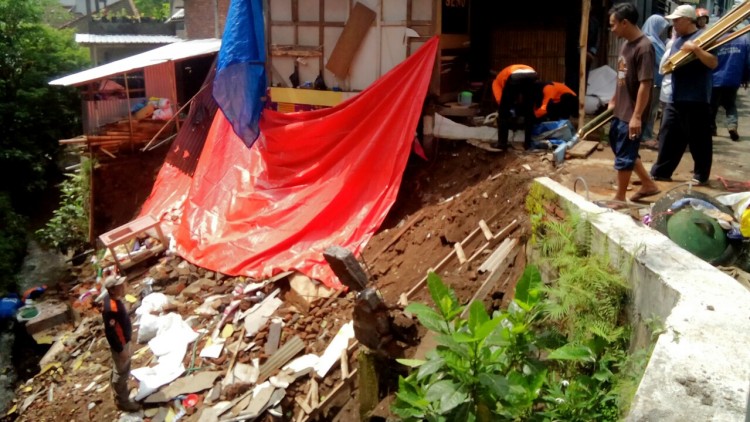 Petugas dari TRC BPBD Kota Batu, Tagana Kota Batu dan warga membersihkan puing longsor di Desa Beji Junrejo, Jumat (2/2). (Aziz / MVoice)