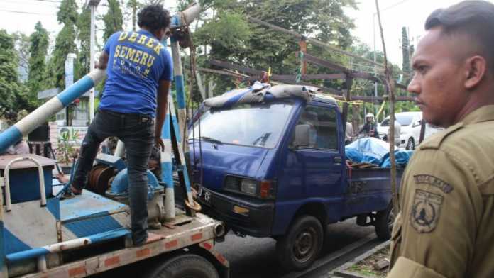 Petugas Satpol PP menertibkan kendaraan yang dipakai untuk berdagang di pinggiran Jalan Panglima Sudirman Kota Batu, Kamis sore (15/3). (Aziz / MVoice)