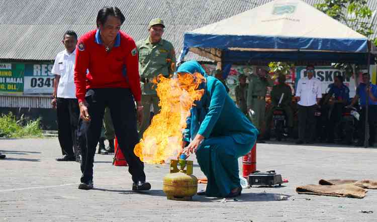 Ibu PKK Desa Mojorejo mencoba memadamkan api dari tabung LPG 3kg, Rabu (25/7). (Aziz Ramadani/MVoice)