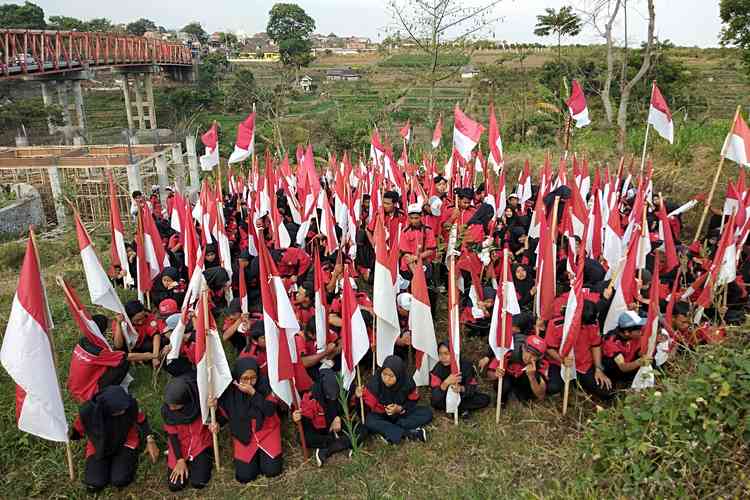 Ratusan siswa SMKN 2 Batu mengibarkan bendera di Kali Lanang, Kota Batu, Jumat (16/8). (Foto: Ayun/MVoice)