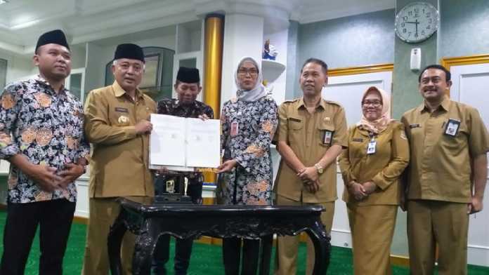 Ketua KPU Kabupaten Malang Anis Suhartini (Kanan/baju batik dan berjilbab) saat bersama Bupati Malang HM Sanusi, menunjukkan hasil penandatanganan NPHD. (Istimewa/Humas)