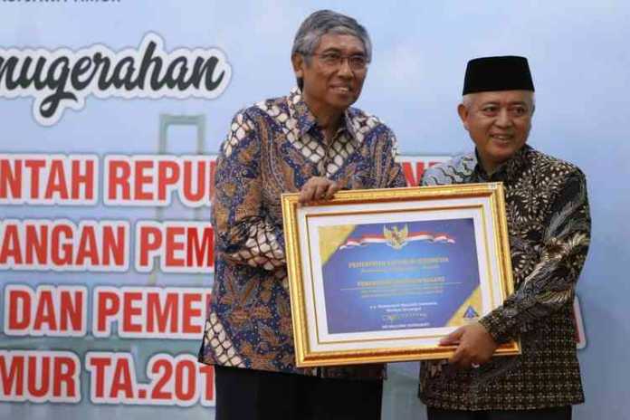 Bupati Malang HM Sanusi (berkopiah) saat menerima penghargaan dari Wakil Menteri Keuangan Republik Indonesia, Mardiasmo. (Istimewa/Humas).