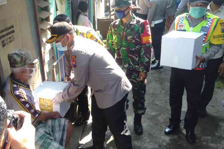 Kapolres Malang AKBP Hendri Umar saat memberikan bantuan paket sembako pada Ponidi. (Toski D)
